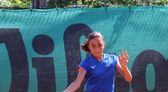Giovane tennista colpisce la palla con grinta su campo in terra rossa.