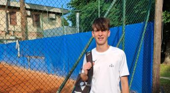 Giovane tennista sorridente con borsa Yonex su campo da tennis.