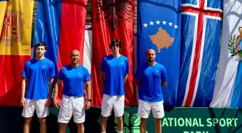 Quattro uomini in divise blu, bandiere colorate sullo sfondo, atmosfera di competizione sportiva.
