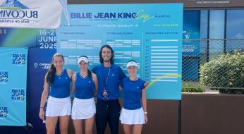 Squadra di tennis felice davanti al tabellone del torneo Billie Jean King Cup.