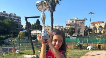 Bambina sorridente con trofeo, orgoglio e felicità in un campo sportivo.
